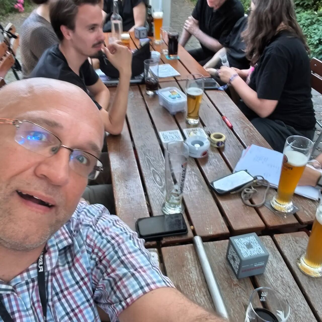 Menschen beim CSD Kick-off Meeting sitzen an einem Holztisch mit Getränken und Notizen.