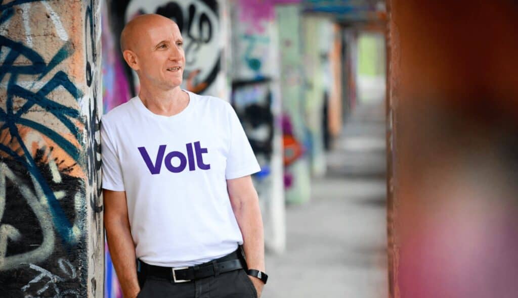 Dirk Bachhausen trägt ein Volt-T-Shirt vor einer Graffiti-Wand in Berlin.