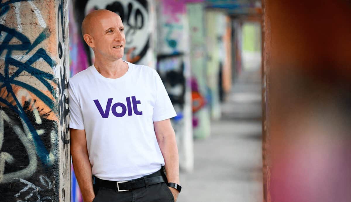 Dirk Bachhausen trägt ein Volt-T-Shirt vor einer Graffiti-Wand in Berlin.