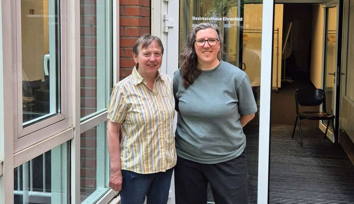 Zwei Frauen vor dem Bezirksamt Ehrenfeld in Köln, freundlich lächelnd.
