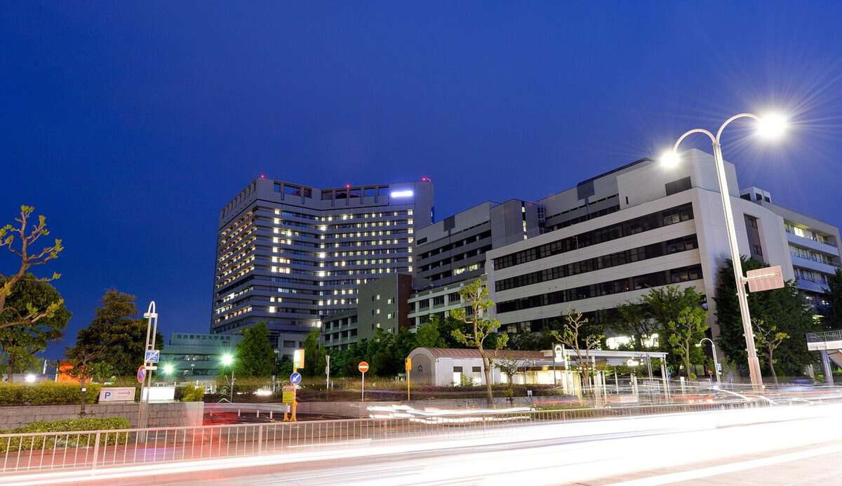 Moderne Krankenhausgebäude bei Nacht mit beleuchteten Fenstern.
