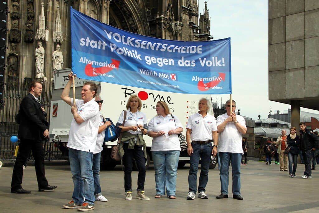 Menschen protestieren mit Transparent gegen Politik in Berlin.