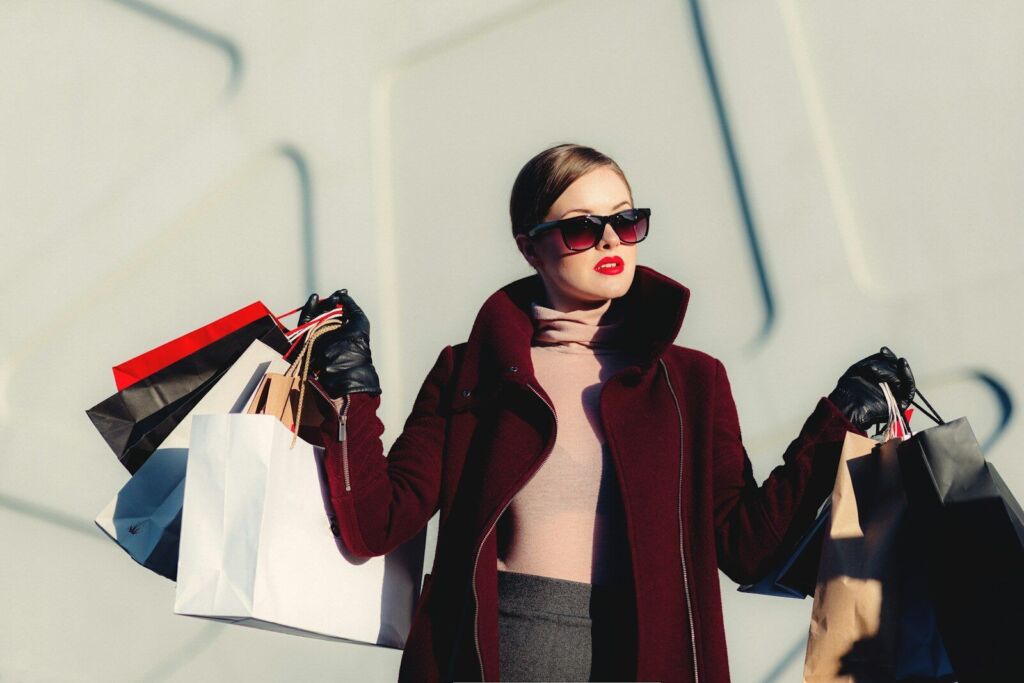 Frau mit Sonnenbrille und Einkaufstüten beim Shopping.