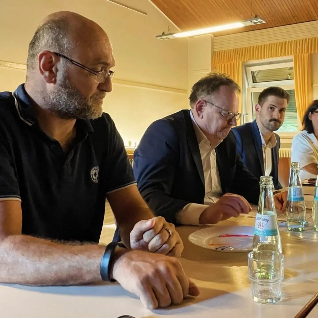 Menschen bei einem Treffen mit dem Oberbürgermeister, diskutieren am Tisch.