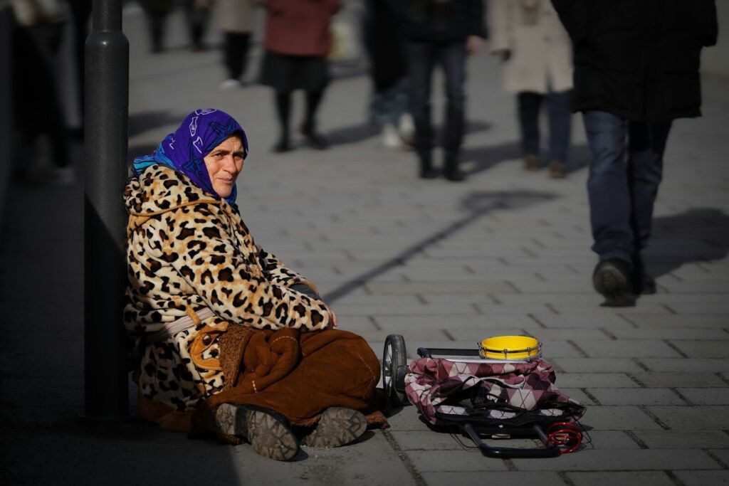 A woman sitting on a sidewalk next to a yellow cup