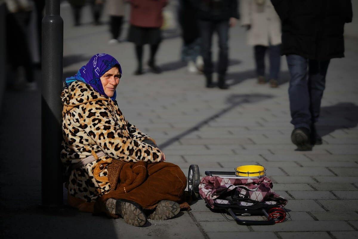 A woman sitting on a sidewalk next to a yellow cup