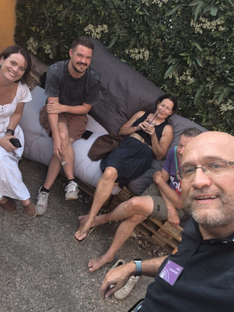 Menschen beim entspannten Treffen im Garten, lachend und plaudernd.