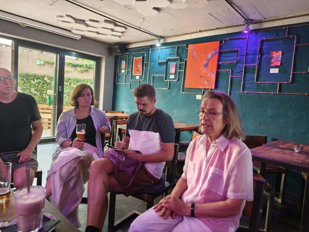 Menschen im Gespräch bei Kindernöte e.V. Treffen in Volt mit moderner Kunst im Hintergrund.