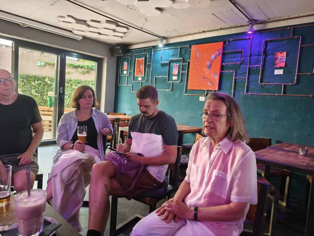 Menschen im Gespräch bei Kindernöte e.V. Treffen in Volt mit moderner Kunst im Hintergrund.