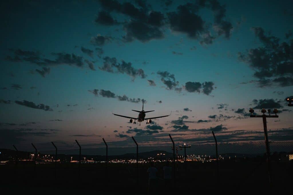 Flugzeug beim Nachtflug über einem Flughafen bei Sonnenuntergang.