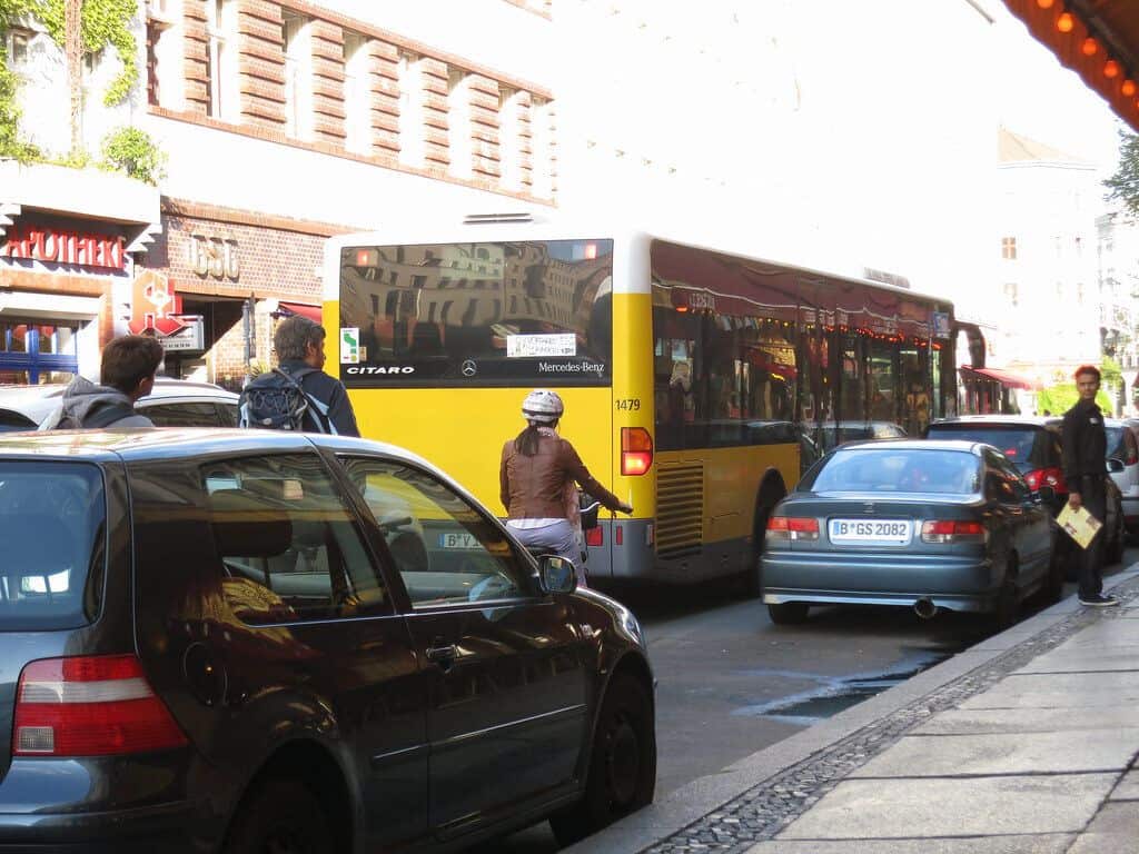 Verkehr in Köln mit Bus, Autos und Fußgängern auf der Straße.