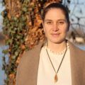 Frau steht am Flussufer mit Baum im Hintergrund, Naturaufnahme.
