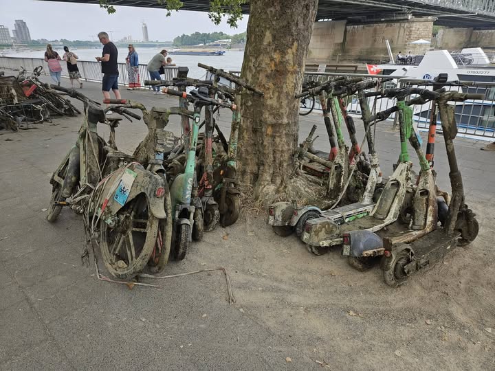 Verrostete, versenkte E-Scooter unter einer Brücke in Köln.