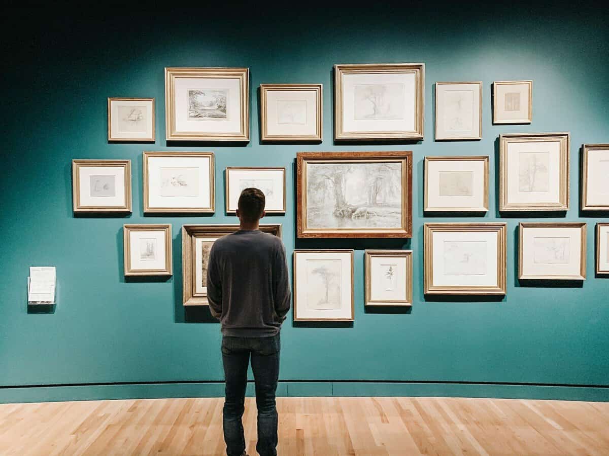 Mann betrachtet Gemälde in Kunstgalerie, Kunstwerke an Wand, Kunstbetrachtung.