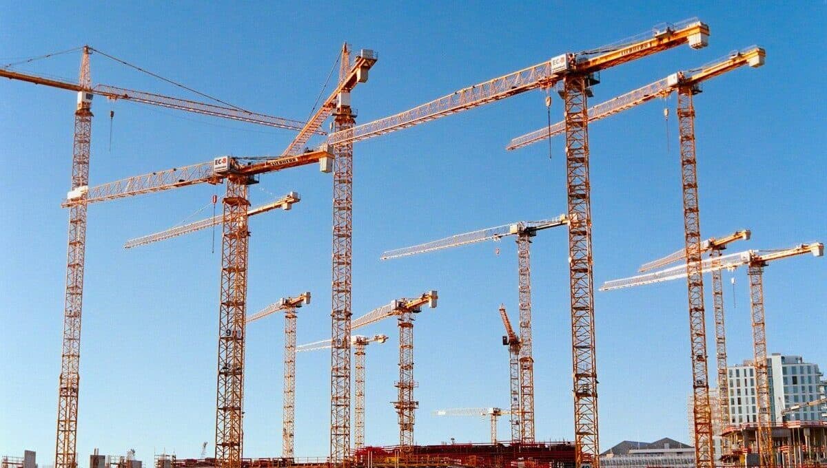 Mehrere Baukräne auf einer Baustelle in der Stadt bei klarem Himmel.