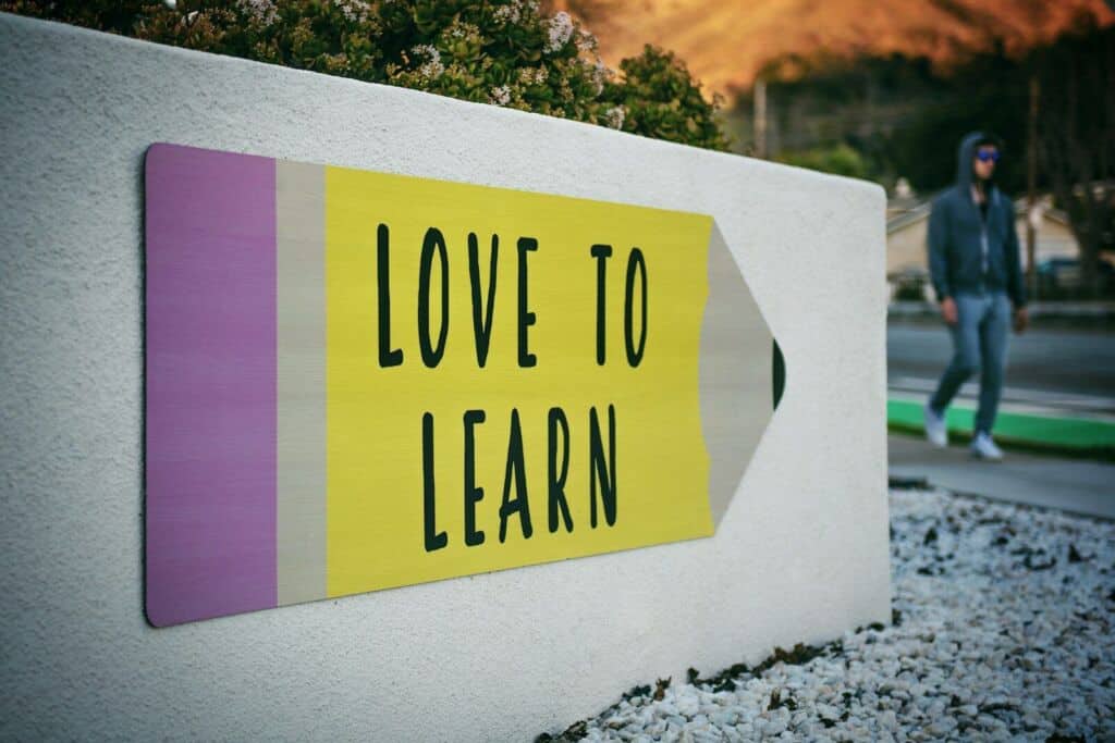 Hinweisschild mit 'Love to Learn' in gelber Farbe an weißer Wand.