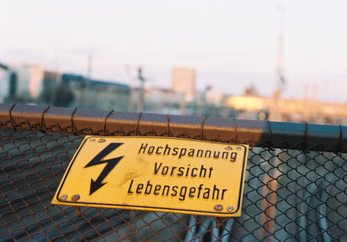 Warnschild mit Hochspannung, Vorsicht, Lebensgefahr auf Zaun.