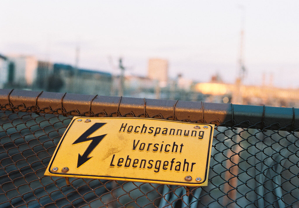 Warnschild mit Hochspannung, Vorsicht, Lebensgefahr auf Zaun.