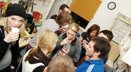 Gruppe junger Menschen in WG-Küche bei Feier in Köln.