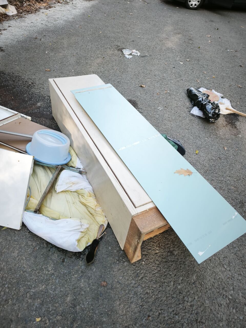 Abfall aus Holz auf Gehweg, Baumaterialien liegen verstreut.
