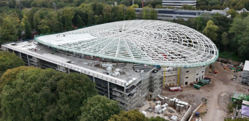 Das Radstadion in Köln im Bau, mit einer großen, ovalen Dachkonstruktion.