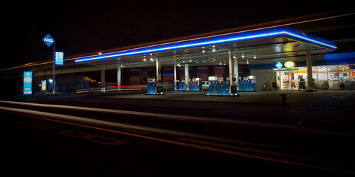Beleuchtete Tankstelle bei Nacht mit Zapfsäulen und Leuchtreklame.