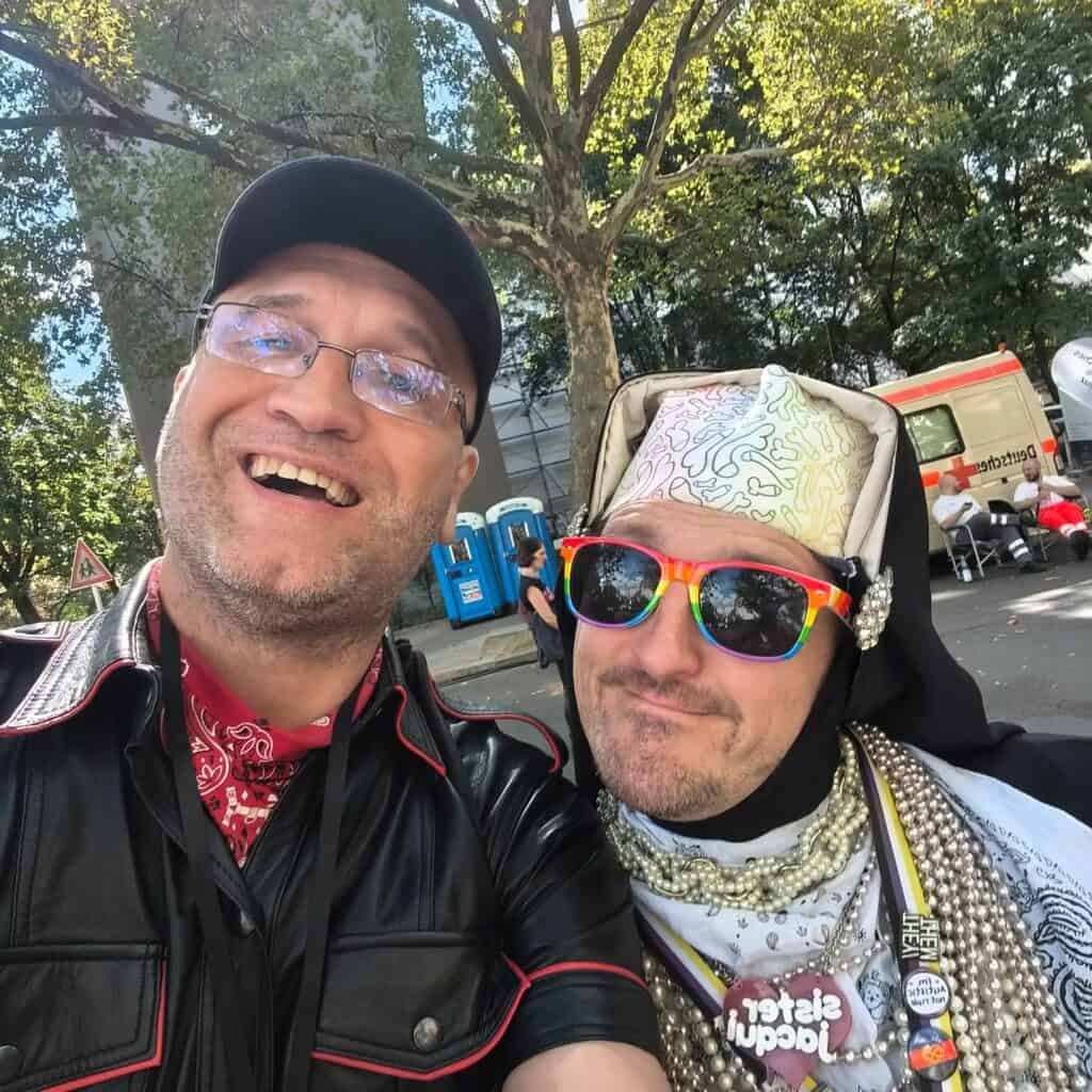 Zwei Männer in bunten Outfits bei Folsom Berlin, feiern und posieren für Foto.
