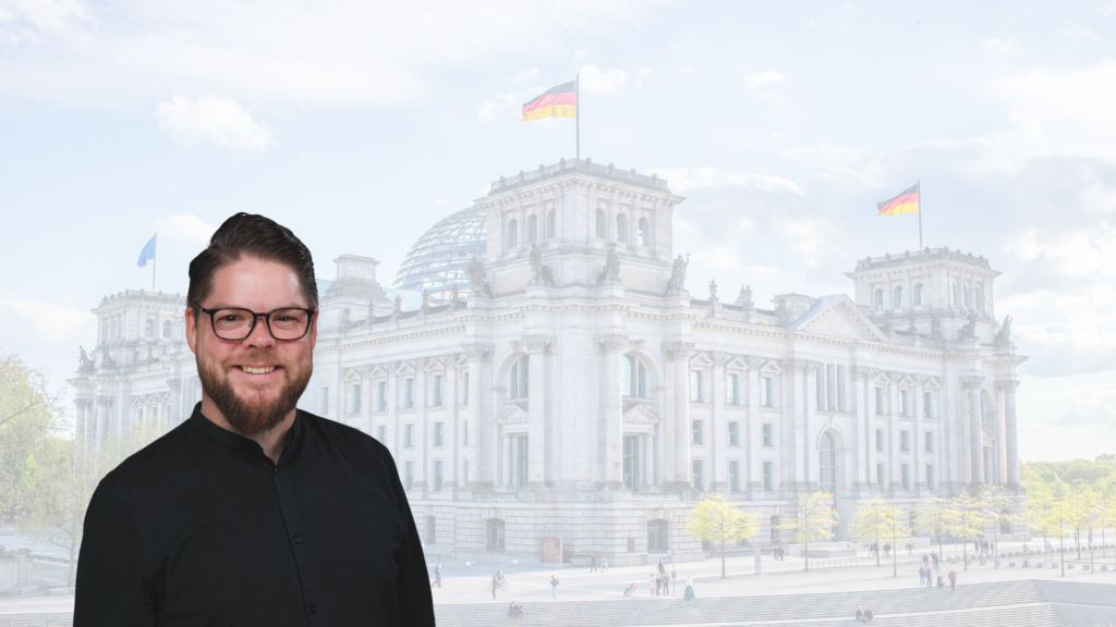 Mann mit Brille vor dem Reichstagsgebäude in Berlin, Deutschland.